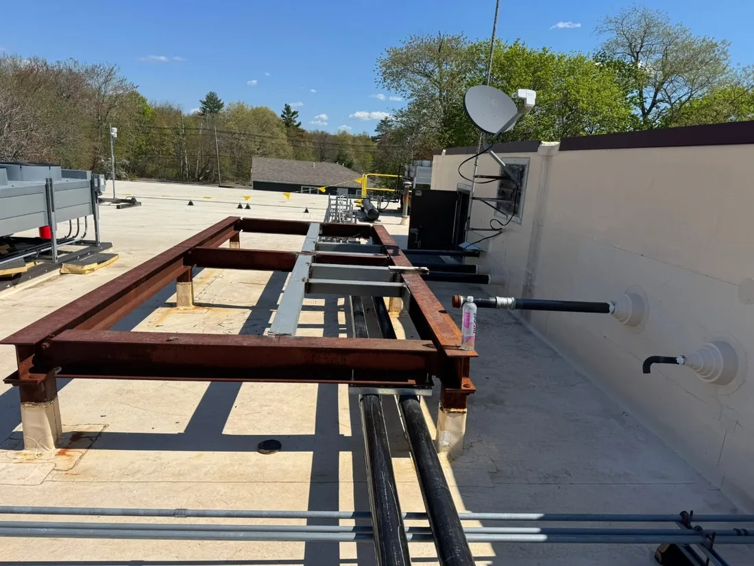 Rooftop grillage steel laid out on sleepers, carrying pipe runs and mechanical services