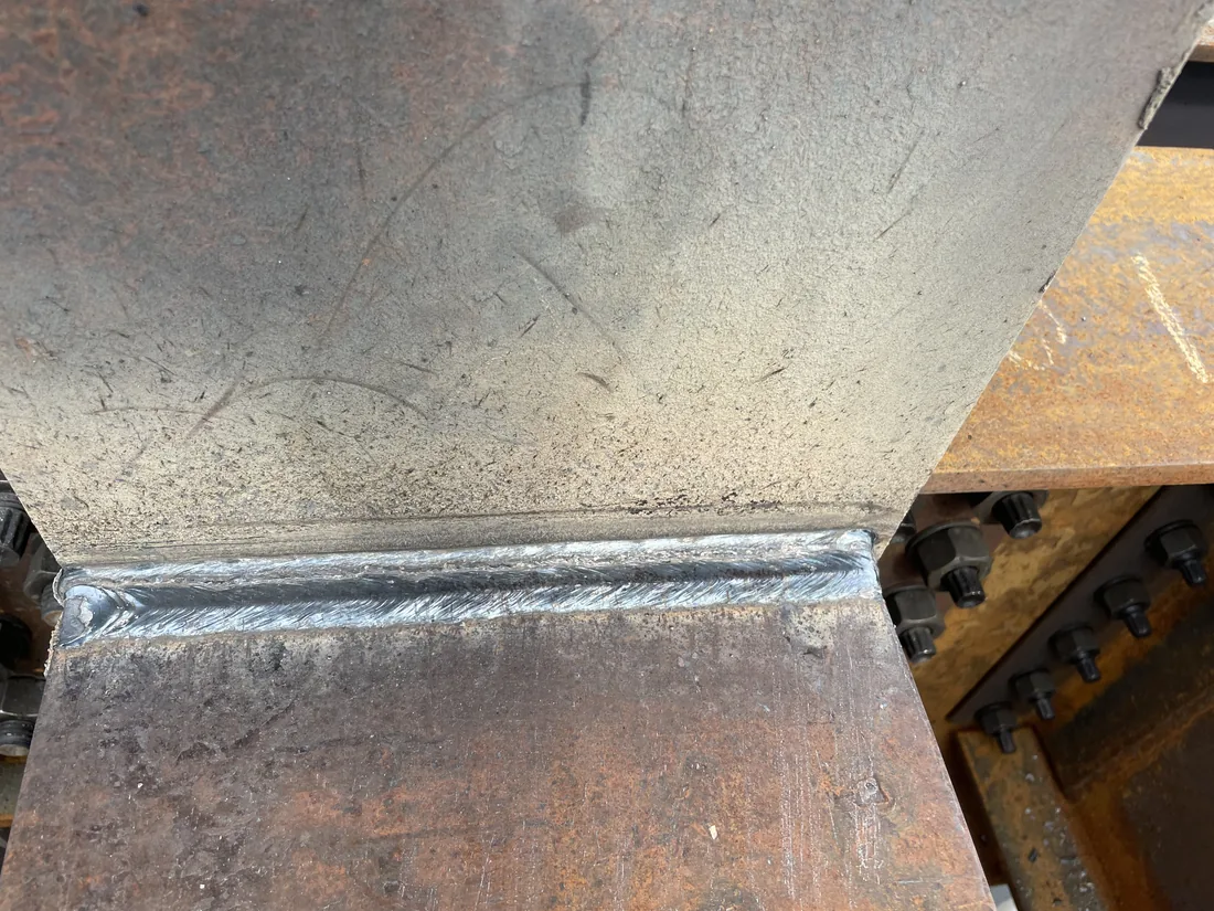 Close up of a completed fillet weld where a steel beam meets a bolted column connection